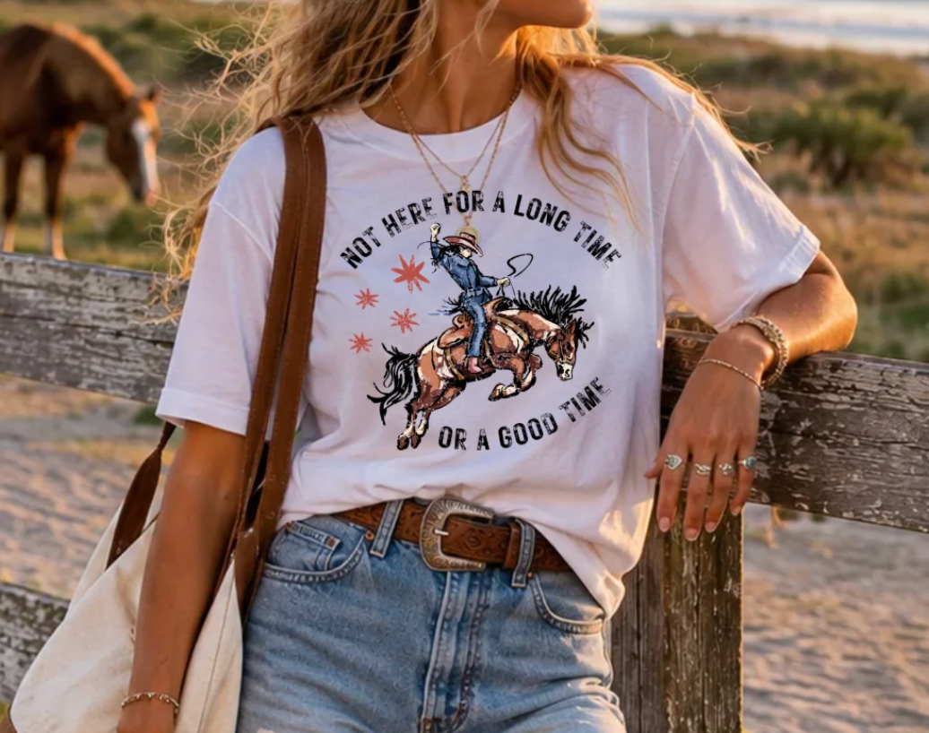 Woman wearing a vintage-inspired horse girl graphic t-shirt in a casual setting with horses. 