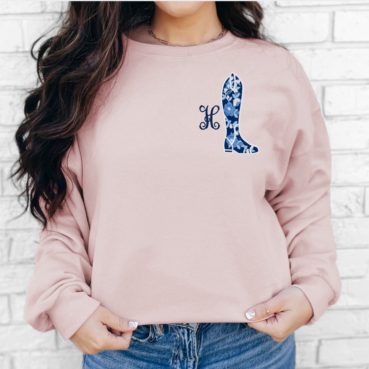 Woman wearing an embroidered equestrian crewneck sweatshirt at the barn.