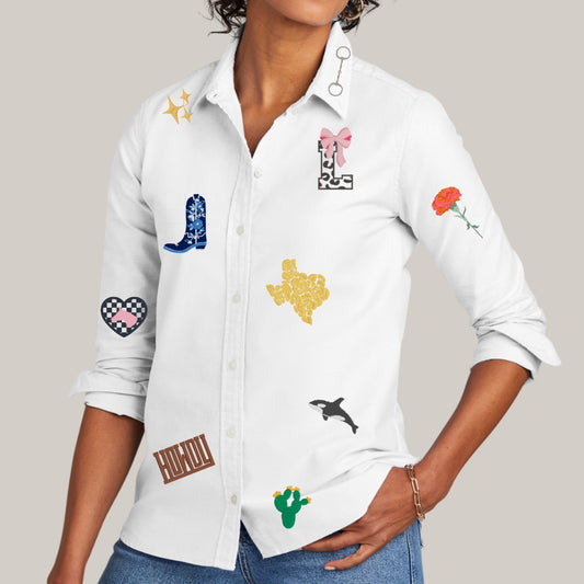White shirt with various embroidered designs worn by a person on a neutral background