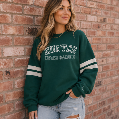 Varsity style crewneck sweatshirt on a horse girl with HUNTER UNDER SADDLE printed on the front