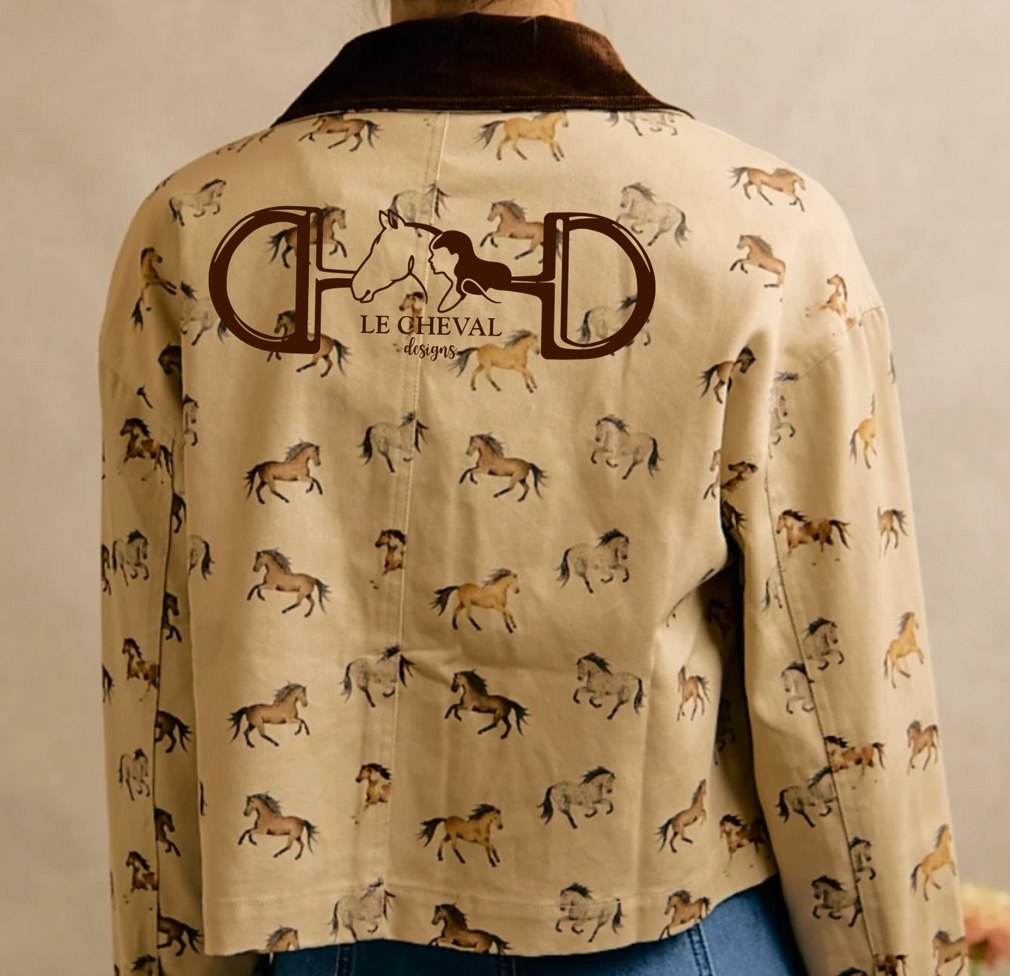 A cropped beige jacket with an allover print of running horses and a dark brown collar, featuring a large 'Le Cheval Designs' logo on the back.