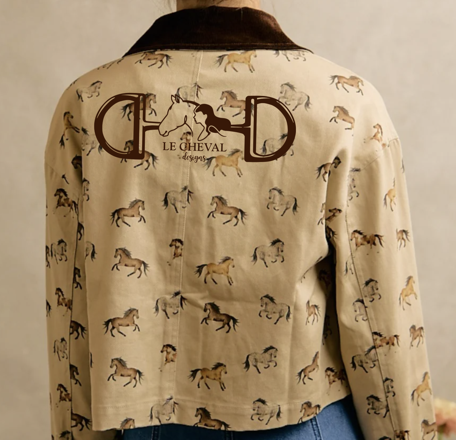 A cropped beige jacket with an allover print of running horses and a dark brown collar, featuring a large 'Le Cheval Designs' logo on the back.